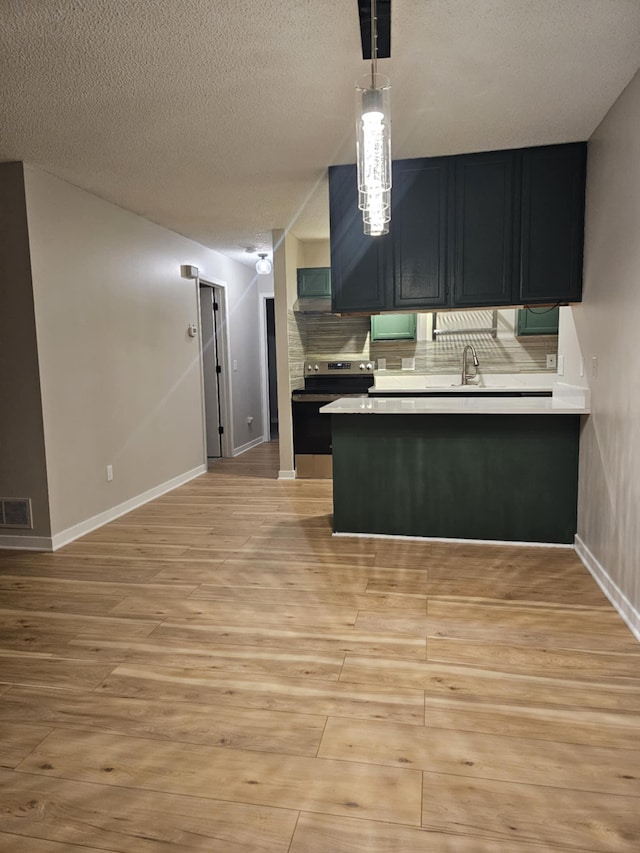 kitchen featuring kitchen peninsula, backsplash, electric stove, pendant lighting, and light hardwood / wood-style floors