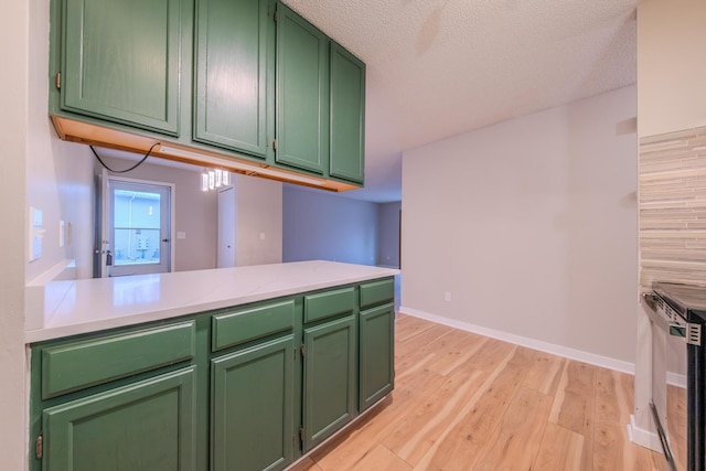 kitchen with kitchen peninsula, light hardwood / wood-style flooring, a textured ceiling, and green cabinetry