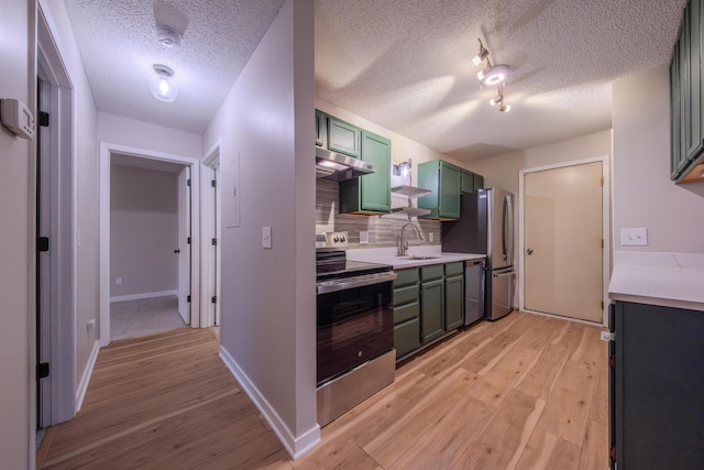 kitchen featuring decorative backsplash, stainless steel appliances, sink, green cabinetry, and light hardwood / wood-style floors