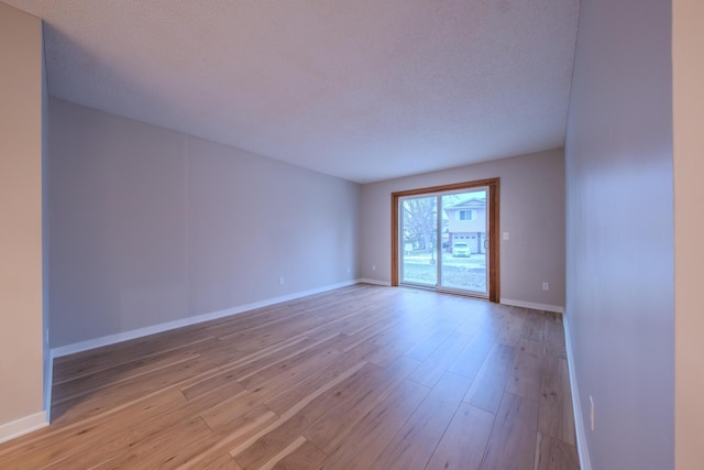 spare room featuring light hardwood / wood-style floors and a textured ceiling