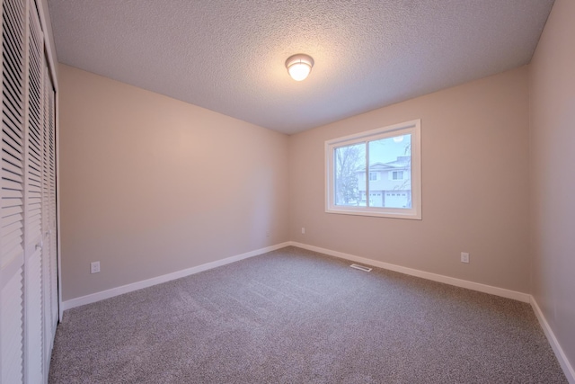 carpeted spare room featuring a textured ceiling