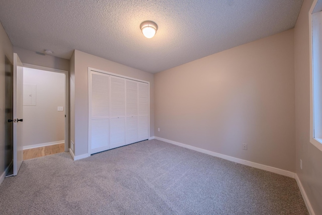 unfurnished bedroom featuring carpet flooring, a textured ceiling, and a closet