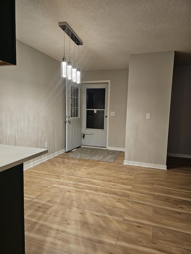 unfurnished dining area featuring a textured ceiling and light wood-type flooring