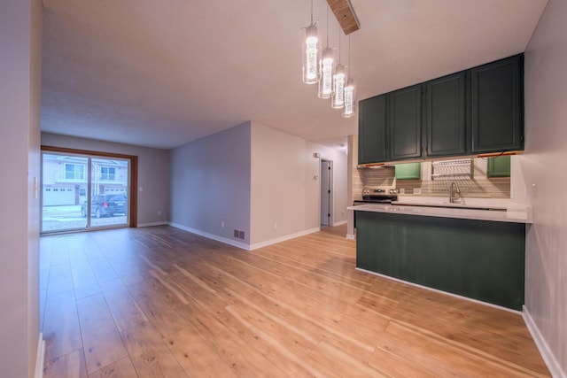 kitchen featuring sink, stainless steel electric range, decorative light fixtures, decorative backsplash, and light wood-type flooring