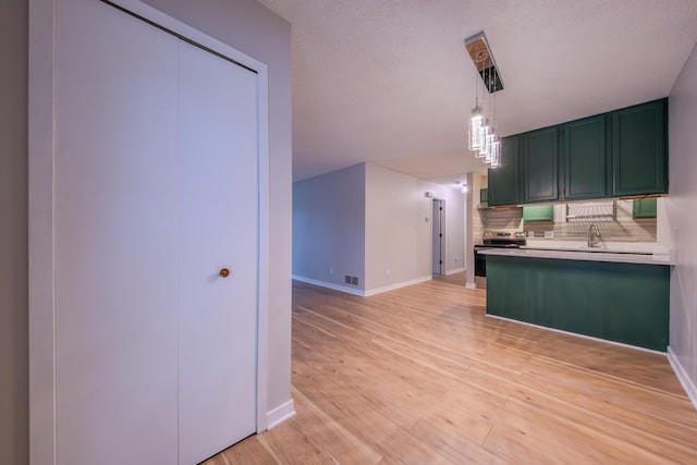 kitchen with hanging light fixtures, tasteful backsplash, green cabinetry, stainless steel electric range, and light wood-type flooring