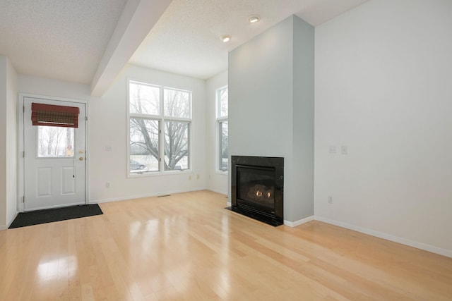 unfurnished living room with hardwood / wood-style flooring and a textured ceiling