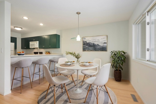 dining room with light wood finished floors, recessed lighting, visible vents, and baseboards