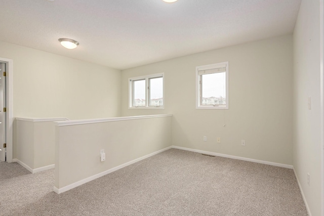 carpeted spare room with visible vents and baseboards