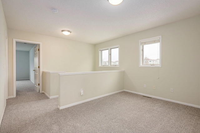 carpeted spare room featuring visible vents and baseboards