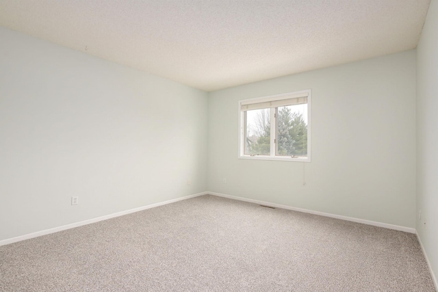 empty room with baseboards, a textured ceiling, and light colored carpet