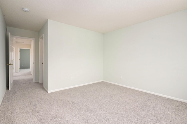 unfurnished room with baseboards and light colored carpet