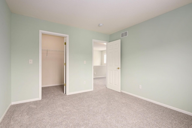 unfurnished bedroom featuring visible vents, baseboards, a spacious closet, a closet, and carpet