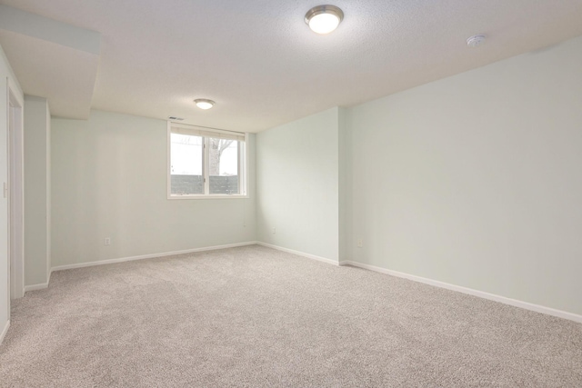 empty room featuring baseboards, a textured ceiling, and light colored carpet