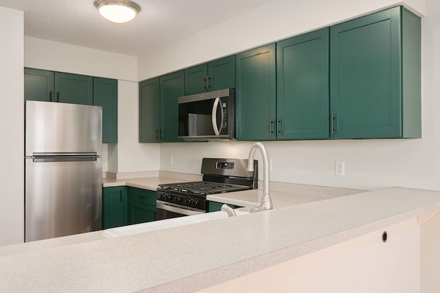 kitchen featuring stainless steel appliances, light countertops, a textured ceiling, and green cabinets