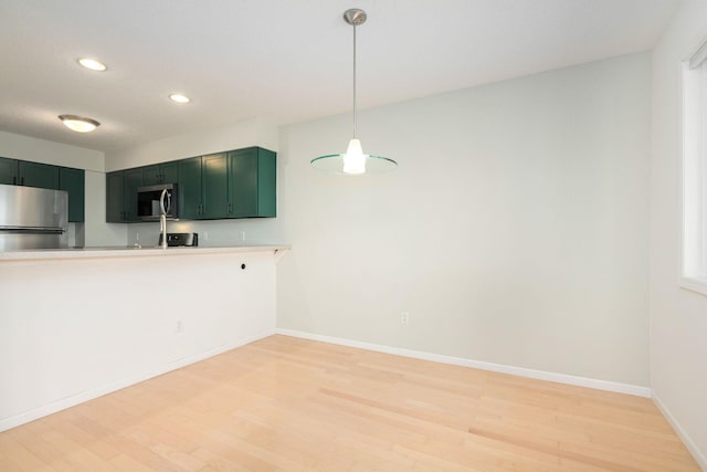 kitchen featuring green cabinets, stainless steel appliances, light wood-type flooring, and light countertops