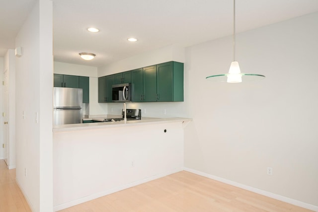 kitchen featuring light countertops, appliances with stainless steel finishes, light wood-style floors, green cabinetry, and baseboards