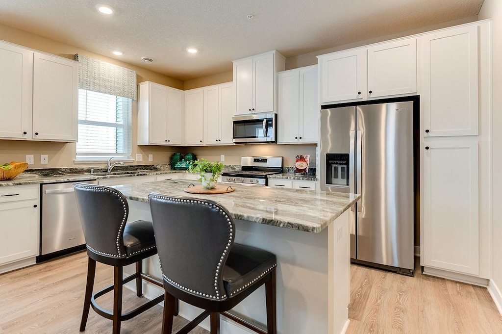 kitchen with a kitchen island, white cabinetry, sink, and appliances with stainless steel finishes