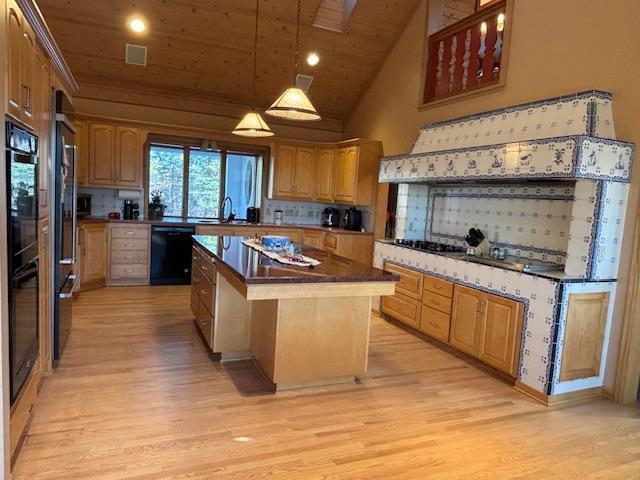 kitchen featuring wooden ceiling, vaulted ceiling, a kitchen island, black dishwasher, and light hardwood / wood-style floors