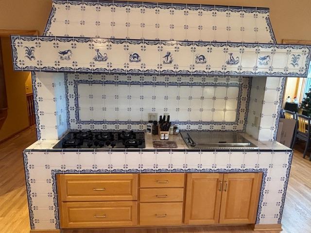 bar with black stovetop and light wood-type flooring