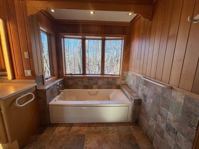 bathroom featuring wood walls, a bathtub, vanity, and tile walls