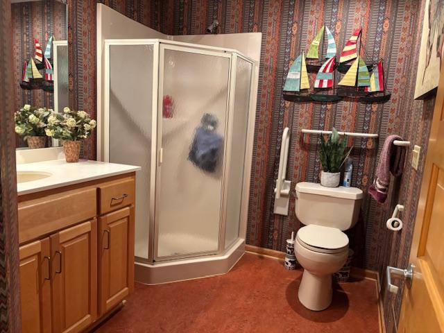 bathroom featuring vanity, a shower with shower door, and toilet