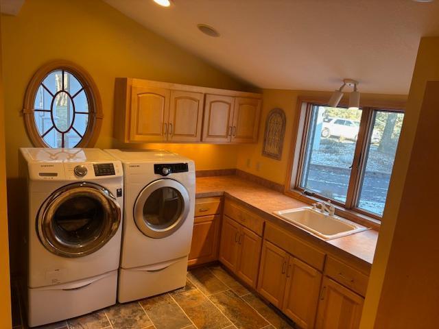 washroom with washing machine and clothes dryer, cabinets, and sink