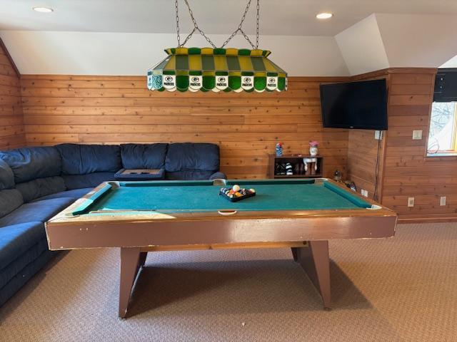 rec room with wooden walls, carpet, vaulted ceiling, and pool table