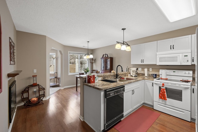 kitchen with sink, white appliances, kitchen peninsula, and white cabinets