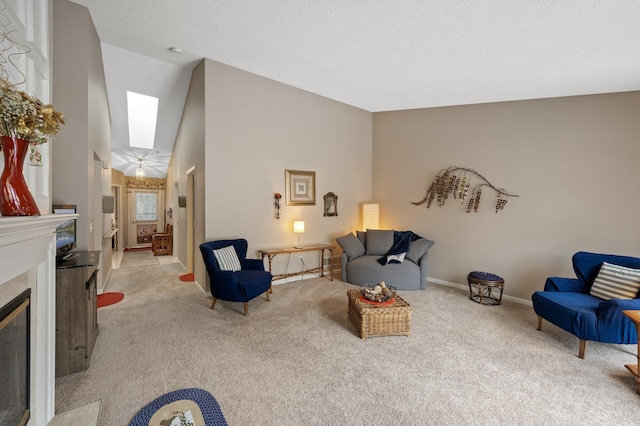 living room with a skylight, high vaulted ceiling, light carpet, a textured ceiling, and a fireplace