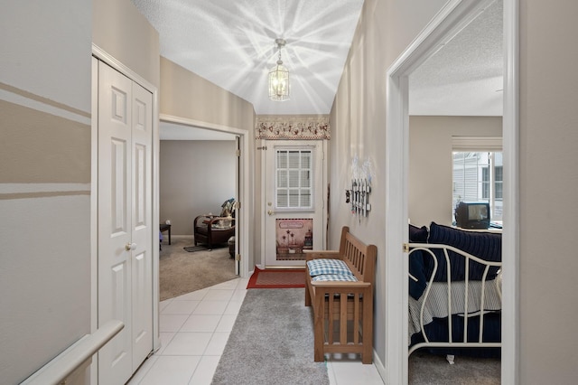 hall with light colored carpet and a textured ceiling