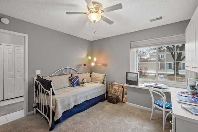 carpeted bedroom with ceiling fan and a textured ceiling