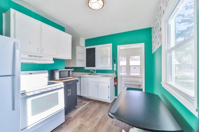 kitchen with white appliances, sink, light hardwood / wood-style flooring, white cabinets, and range hood