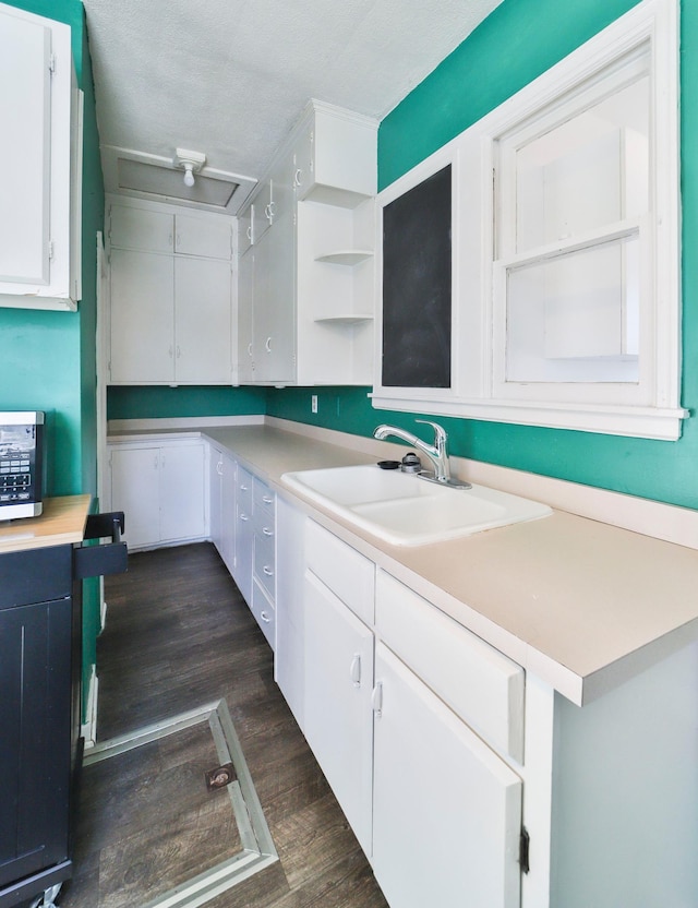 kitchen with a textured ceiling, white cabinetry, dark wood-type flooring, and sink