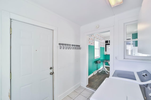 foyer entrance with light hardwood / wood-style flooring, ornamental molding, and washing machine and clothes dryer