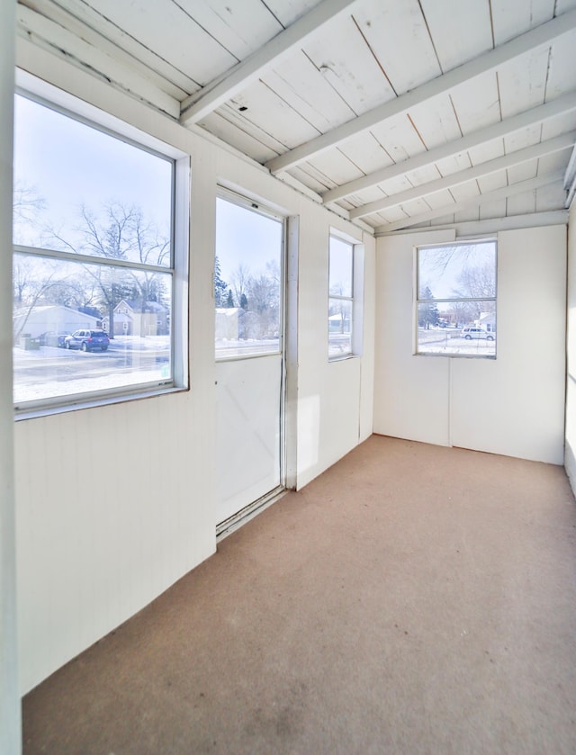 carpeted empty room with beam ceiling and a wealth of natural light