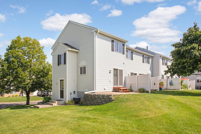 rear view of house with a lawn and central AC