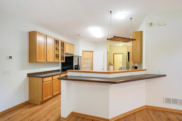 kitchen with a kitchen breakfast bar, kitchen peninsula, light hardwood / wood-style floors, and appliances with stainless steel finishes