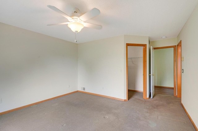 unfurnished bedroom with ceiling fan, a walk in closet, light carpet, and a closet