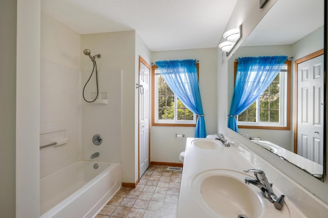 full bathroom with tiled shower / bath combo, a healthy amount of sunlight, toilet, and vanity