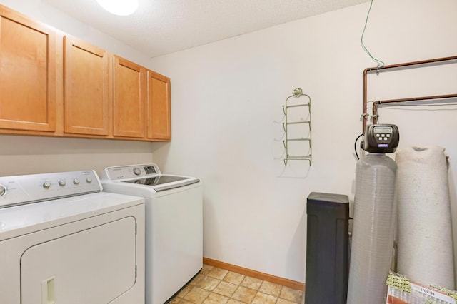 laundry room with washer and clothes dryer, cabinets, and a textured ceiling