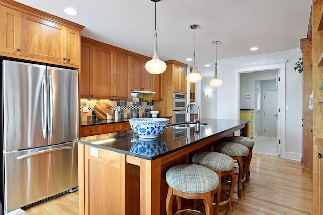 2496 Old Beach Rd, Orono, MN 55391 - kitchen featuring appliances with stainless steel finishes, brown cabinets, a center island with sink, a kitchen bar, and crown molding