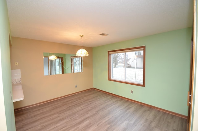 empty room with hardwood / wood-style floors and a notable chandelier