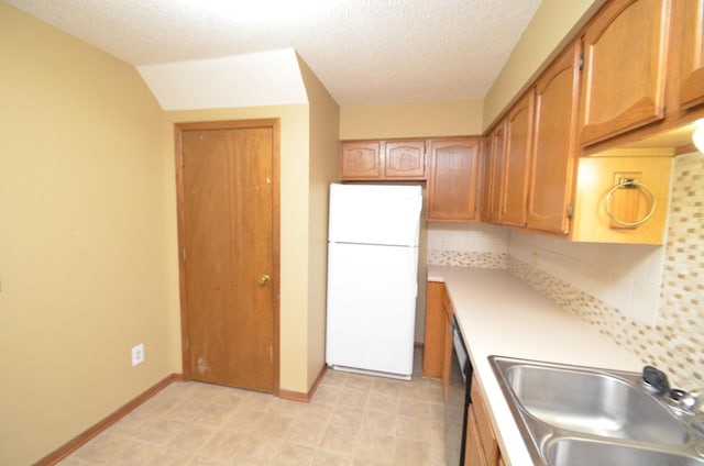 kitchen featuring tasteful backsplash, sink, a textured ceiling, and white refrigerator