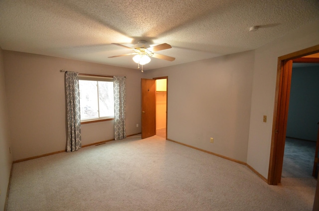 unfurnished room featuring ceiling fan, light carpet, and a textured ceiling