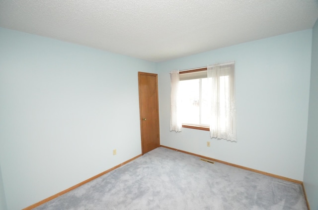 unfurnished room featuring light colored carpet and a textured ceiling