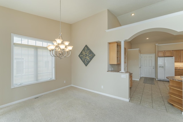 carpeted spare room featuring high vaulted ceiling and an inviting chandelier