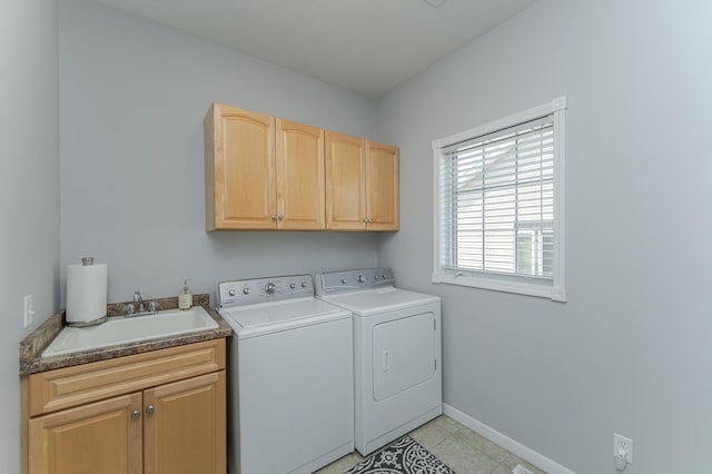 clothes washing area featuring washer and clothes dryer, sink, light tile patterned flooring, and cabinets