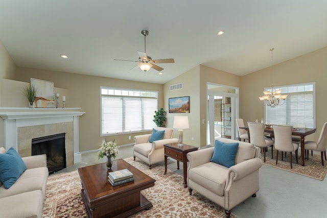 carpeted living room with ceiling fan with notable chandelier, lofted ceiling, and a tiled fireplace