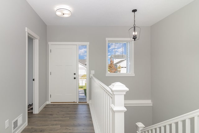 entryway with dark hardwood / wood-style floors and a notable chandelier