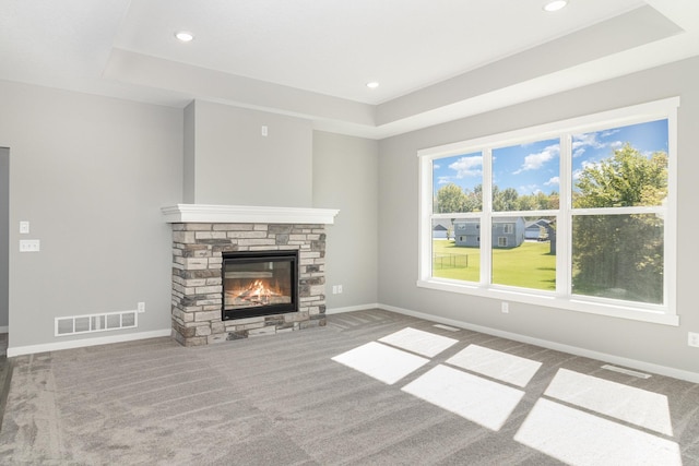 unfurnished living room with carpet flooring, a raised ceiling, and a fireplace